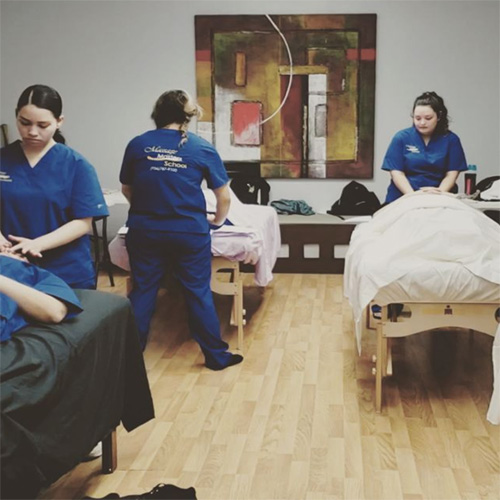 Students practicing hands-on massage techniques in the Massage Masters School clinic